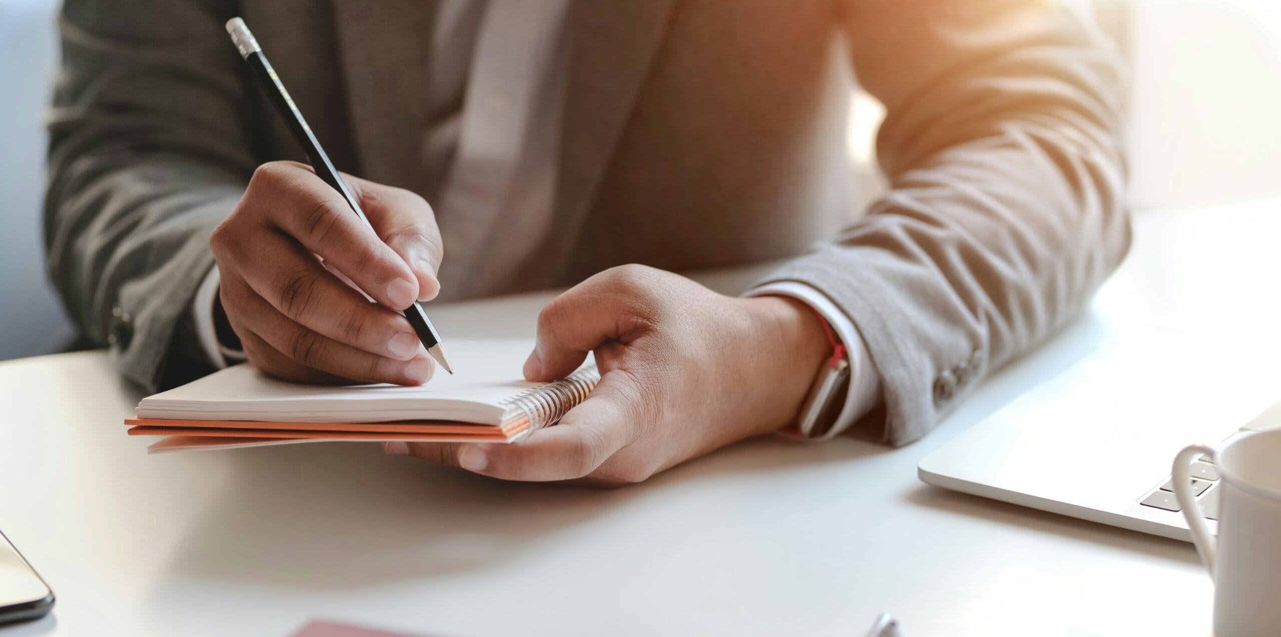 Businessperson writing notes in notebook at desk