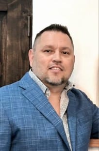 Man in blue plaid blazer smiling indoors