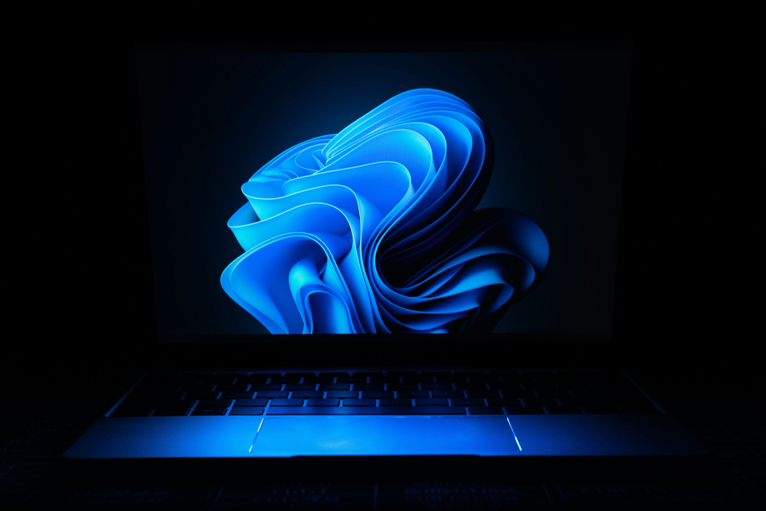 Laptop screen displaying abstract blue digital wallpaper
