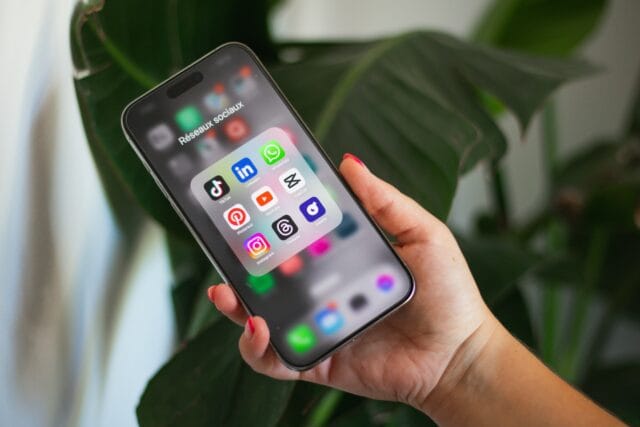 Hand holding smartphone displaying social media apps