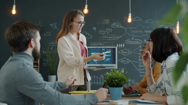 Woman presenting marketing data to team in office